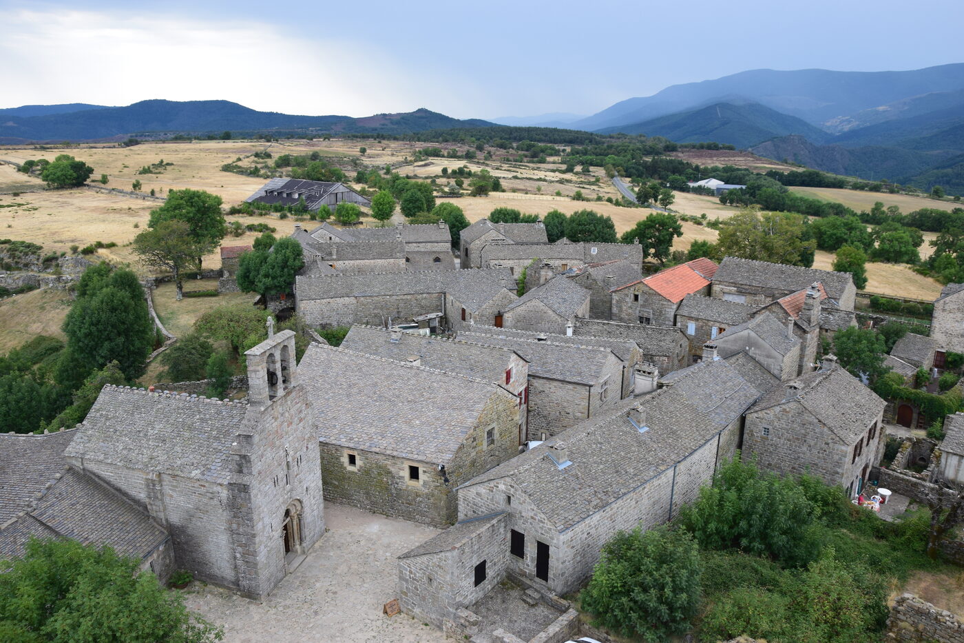 Les toits de lauzes du hameau fortifié de La Garde-Guérin et son église romane, sur le plateau au-dessus du Chassezac