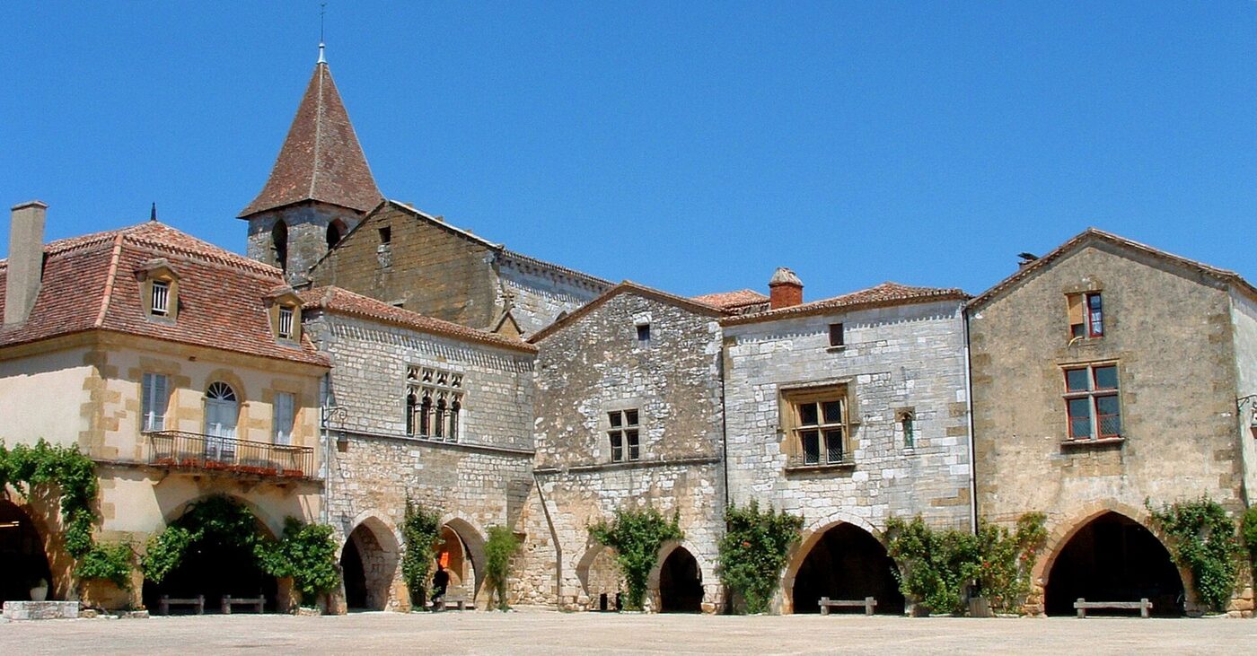 La place des Cornières de Monpazier bordée d'arcades, avec l'église Saint-Dominique
