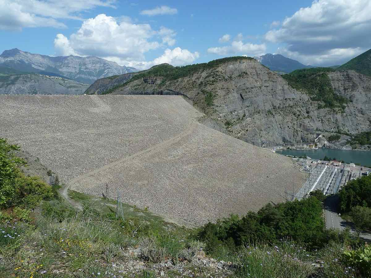 La digue en enrochement du barrage de Serre-Ponçon vue depuis le belvédère, avec la centrale EDF à son pied