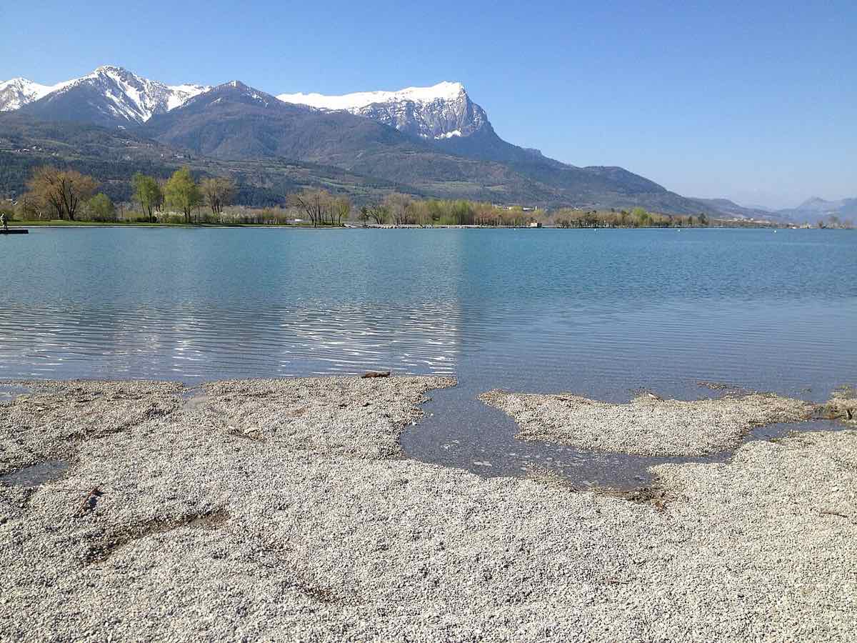 La plage de galets du plan d'eau d'Embrun face aux sommets enneigés