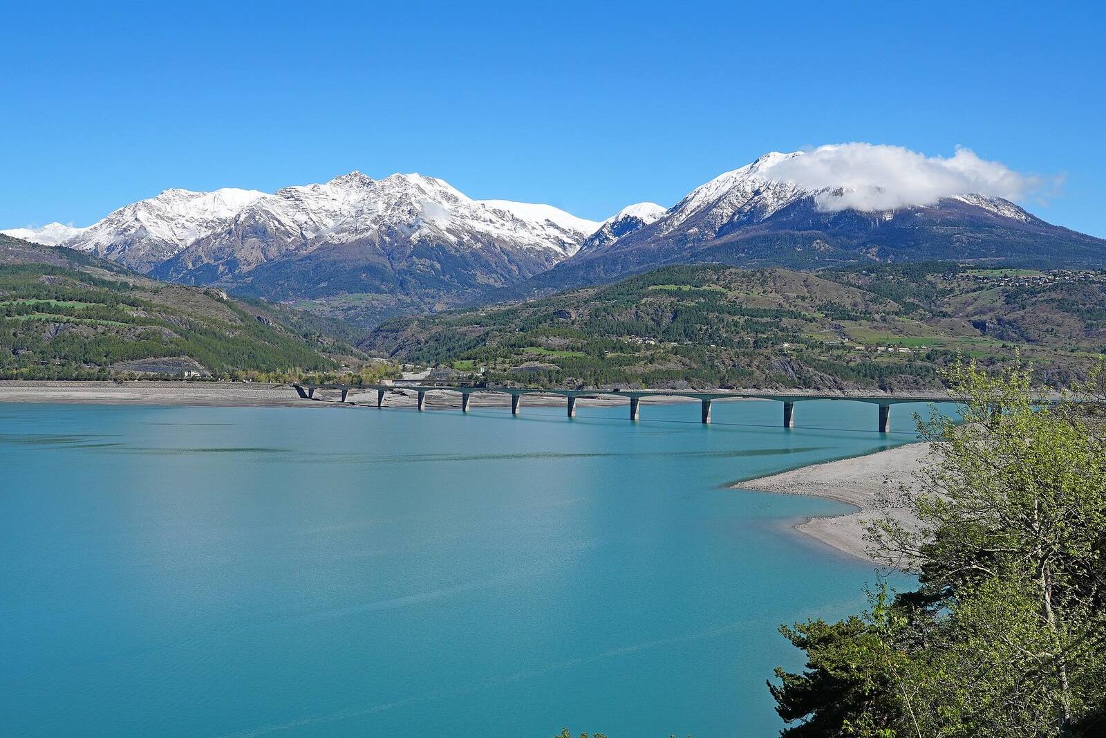 Le pont de Savines-le-Lac franchissant le lac de Serre-Ponçon, avec les sommets enneigés en arrière-plan